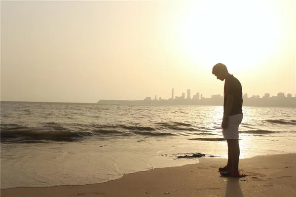 Одинокий мужчина стоит на берегу моря