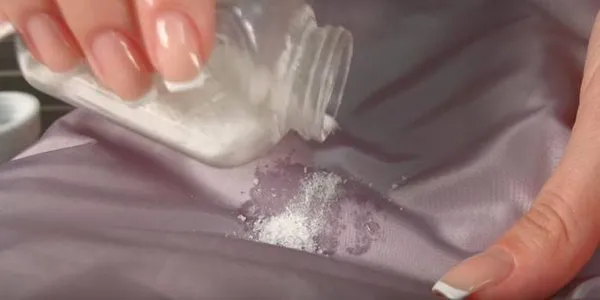Женщина сыпет соль на пятно
