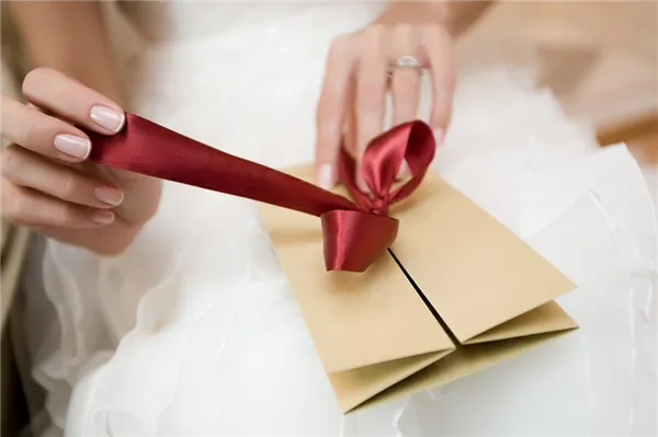 Невеста развязывает ленту на конверте