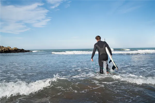 young-surfer-entering-into-the-water-with-his-surfboard-in-a-black-surfing-suit-sport-and-water-sport-concept.jpg